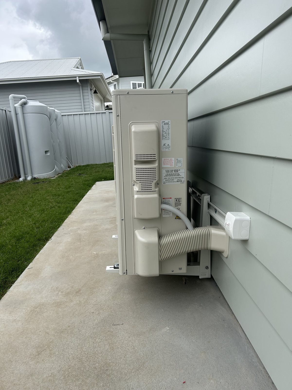 Outdoor condenser unit with neat conduit and pipework under the eave of a Clarence Valley home